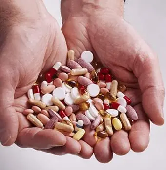 Assorted pills and supplements held in hands